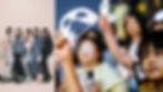 O grupo NewJeans, composto por cinco integrantes, de um lado e mulheres coreanas protestando com máscaras brancas na mão.