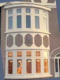Exterior shot of a white bay window with architectural details on building.
