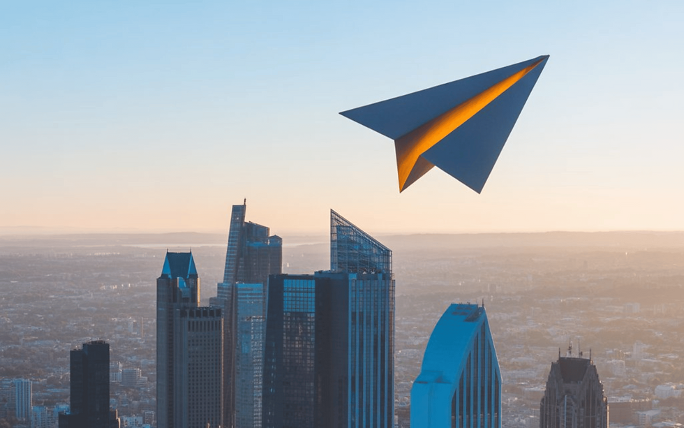 Paper plane flying over a city skyline in NorthBeam Studio brand colors, as our Office contact background
