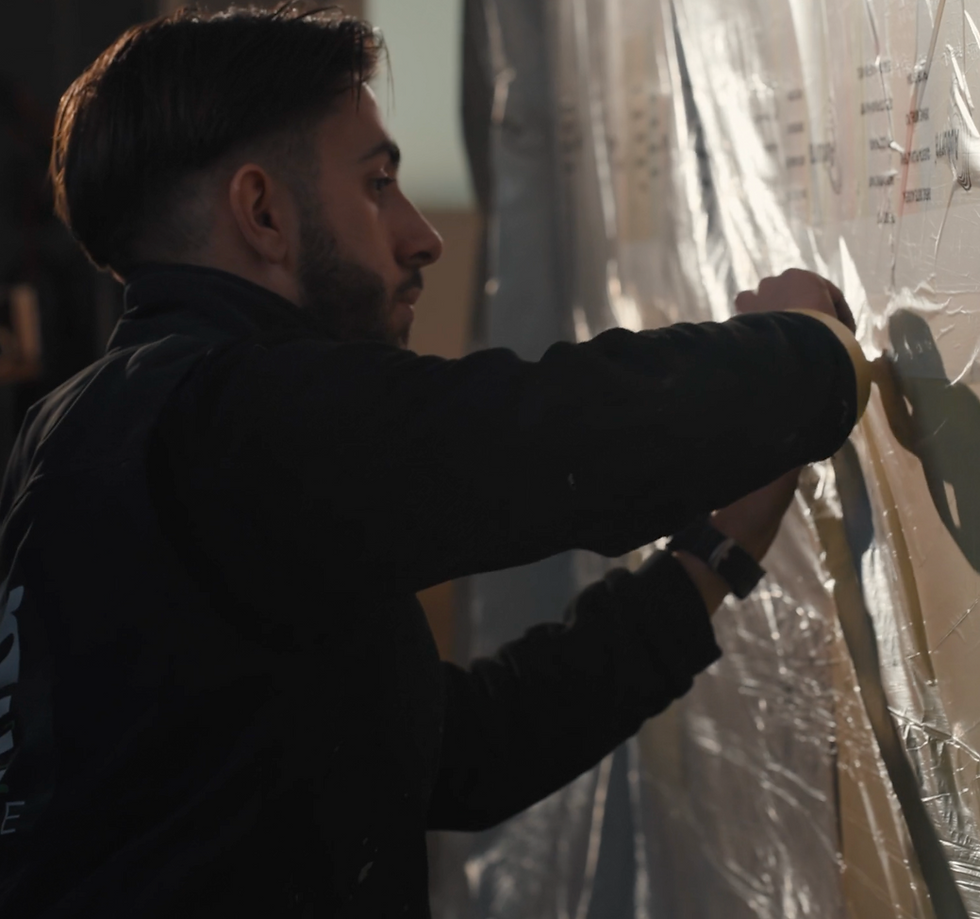 Homme barbu de profil travaillant sur un tableau mural.