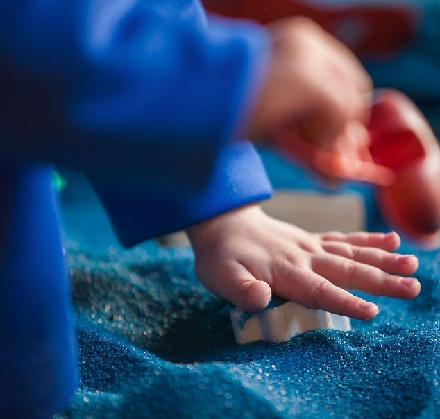 Criança brincando com areia azul