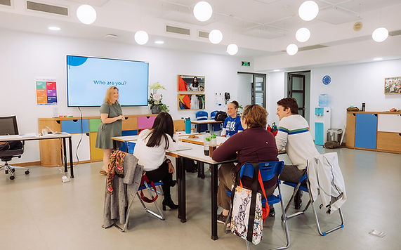 Anna holds a workshop in a school classroom with four adults around a square table