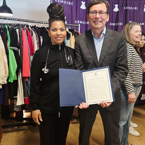 Quiana Daniels in Childress Nursing Services scrubs holding signed Executive Order 26-01 alongside Washington Governor Bob Ferguson