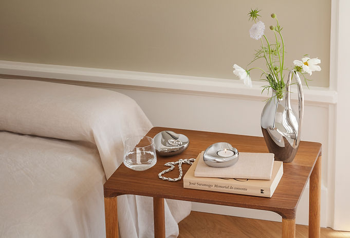 a bedside table with a beautiful silver heart and candle sitting on it