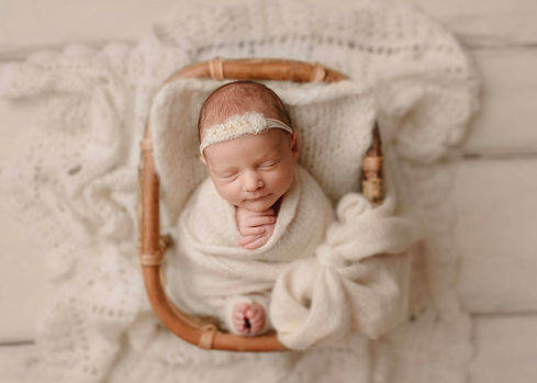 noworodek owinięty z biały kocyk z białą opaską na głowie na białych deskach, zdjęce wykonane podczas szkolenia fotograficznego z sesji noworodkowej w studio fotograficznym 