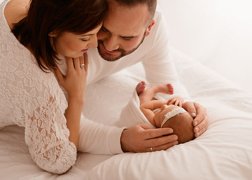 rodzice trzymają noworodka podczas sesji noworodkowej fotograficznej 