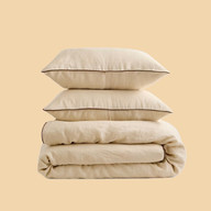 Stack of cream cotton bedding, including pillows, duvet, and sheets.