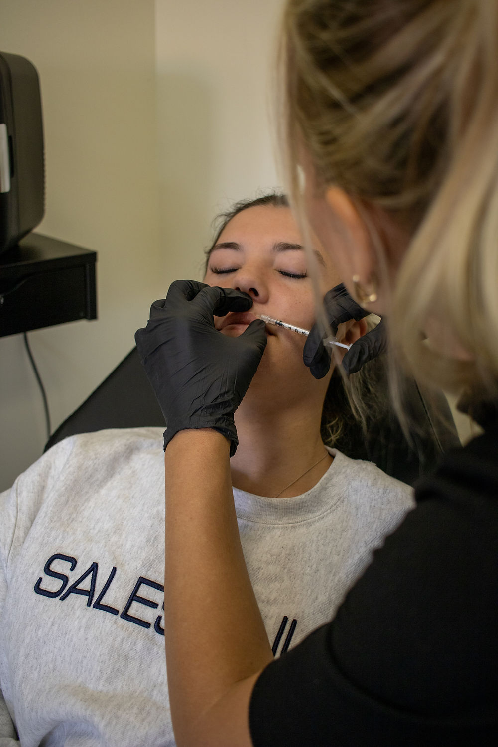 Provider performing lip flip injection during aesthetics event