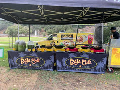 Baja Cali catering setup under a canopy tent with branded tables, drinks, and food service stations.