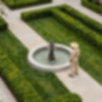 Gardener in straw hat by fountain in formal garden