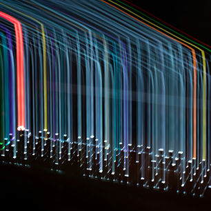 A long exposure of multicolored lights moving down a black background.
