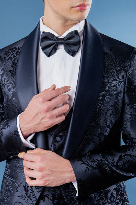 Gros plan revers châle satin et nœud papillon sur brocart bleu – détail smoking Hosana, Cannes.