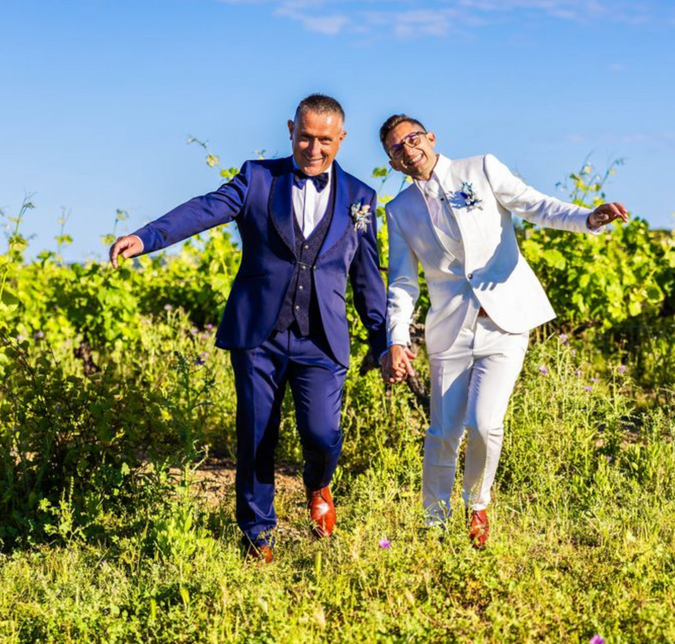 Stéphane et Jonathan le jour de leur mariage, portant des costumes bleu et blanc de Hosana Showroom.