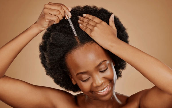 black women applying hair oil, black woman applying hair oil, best hair oils for women, femme noire appliquant de l'huile capillaire, huile capillaire, afro, femme noire, cheveux africains, cheveux 4c, 4c hair, woman with 4c hair