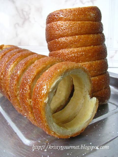 Chimney Cake - Break through the sweet crunchy coating to discover the soft sumptuous interior of this Hungarian festival treat. A Chimney Cake is made of a milk-based raised dough comprised of vanilla, butter, and sugar and topped with a variety of savory toppings including cinnamon, walnuts, coconuts and chocolate. This sweet dough is rolled around a stainless steel roll and then dipped in sugar which caramelizes as it bakes in a special charcoal oven to yield a delectable sensation.