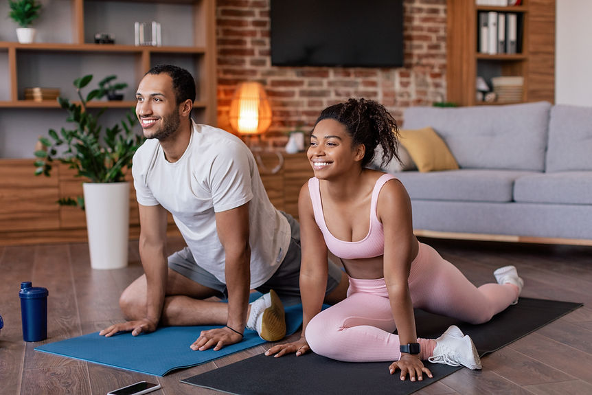 Satisfied young african american guy and lady in sportswear doing leg stretching and pract