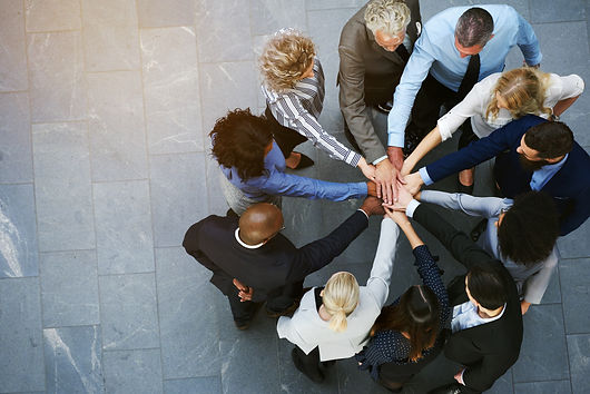 High angle view of a team of united coworkers standing with their hands together in a hudd