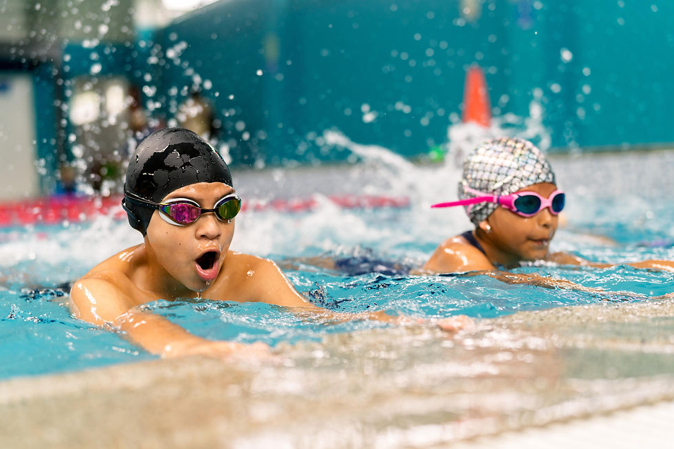 Two swimmers with caps and goggles compete in a pool, splashing water. The background is blue, creating a dynamic and focused atmosphere.