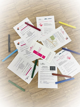 Kursausschreibungen von Sabina Teuscher und Flyer vom Verein Pallas liegen durcheinander auf einem Holztisch. Das Thema dieser Kurse ist Selbstbehauptung und Selbstverteidigung.