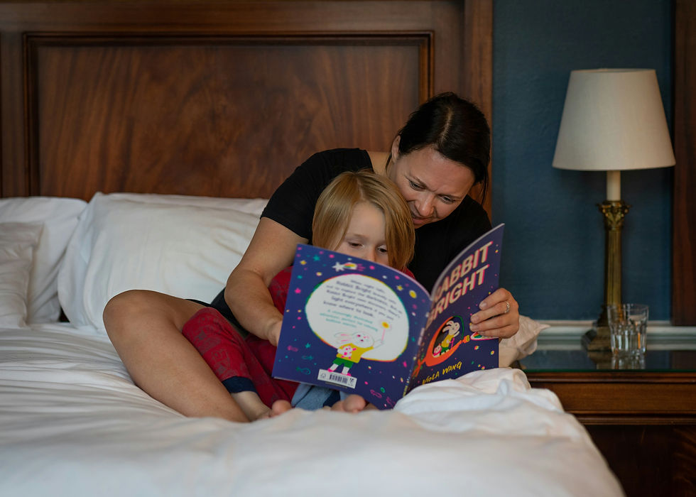 Mother reading a bedtime story to her child in a softly lit bedroom – a reminder of the calming routines we give children, and often forget to give ourselves.