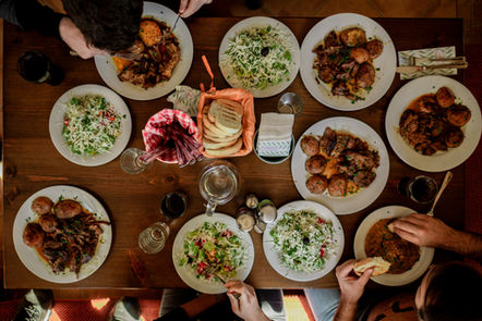 looking down on a selection of white plates on a table, all with different foods on them