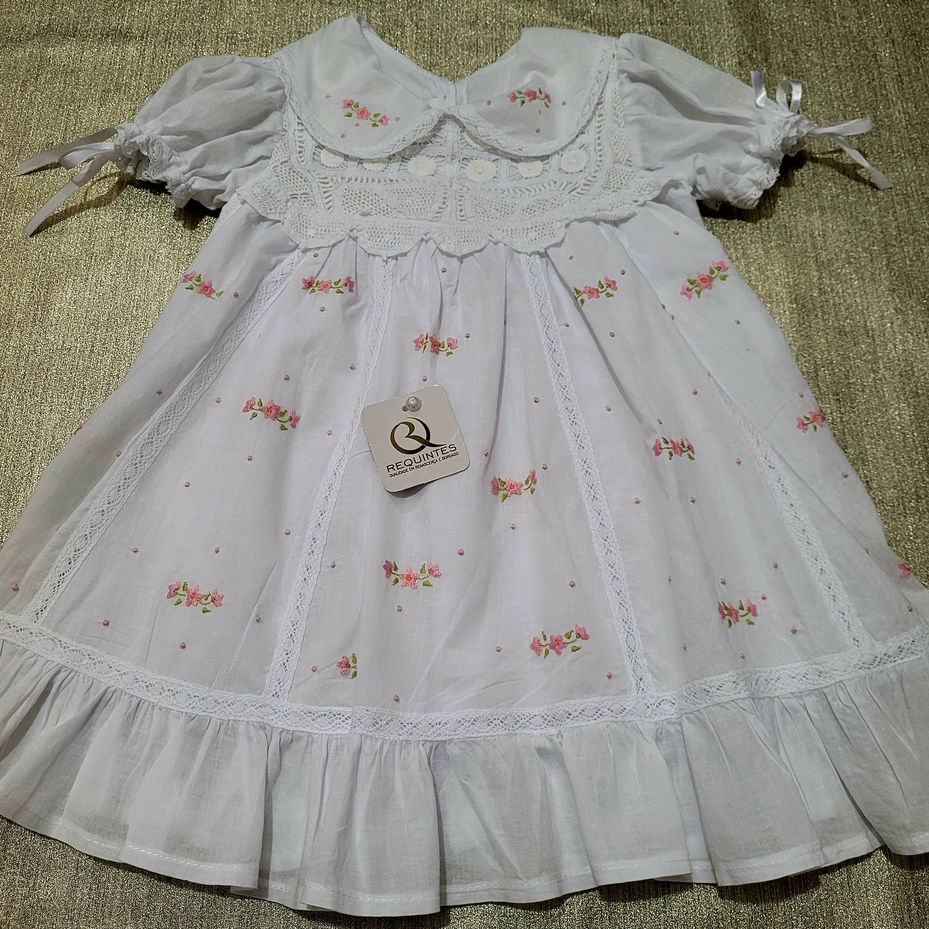 Vestido para bebê com bordados manuais e rendas finas.
