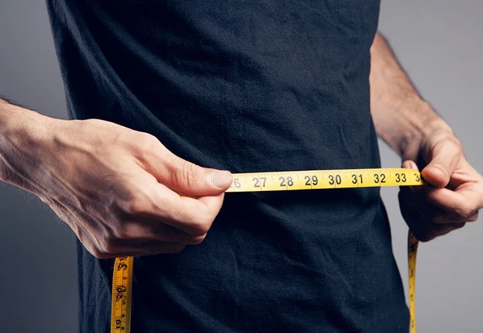 A man measuring his waist for fat loss.
