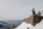 A couple in snowshoes looks out over the Adirondack Mountains in the winter. They stand atop a mountain near Lake Placid, NY during their winter elopement.
