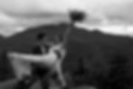 A groom carries his bride while she smiles ecstatically holding her bouquet in the air. The couple is eloping on Mount Jo in the Adirondacks.