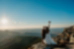 A bride kisses her husband while holding her bouquet in the air. They are eloping on Whiteface Mountain in the Adirondacks.