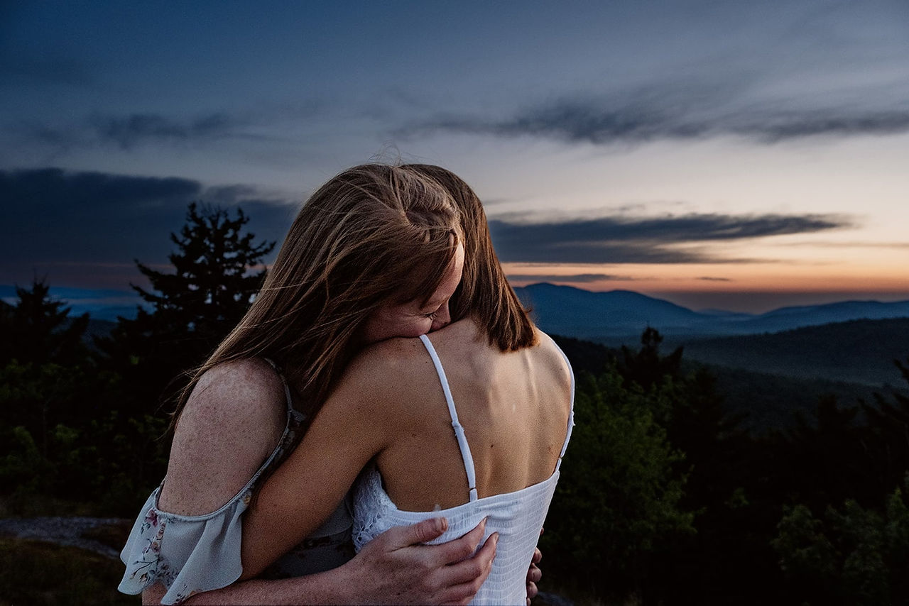 A lesbian couple embraces during their engagement photo session in the Adirondacks.