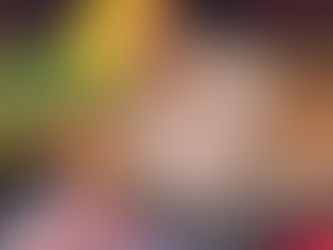 A chocolate orange cocktail served in a highball glass over ice, topped with an orange wheel dipped in Cocoa Caliente, with warm holiday lighting highlighting the rich chocolatey colour.