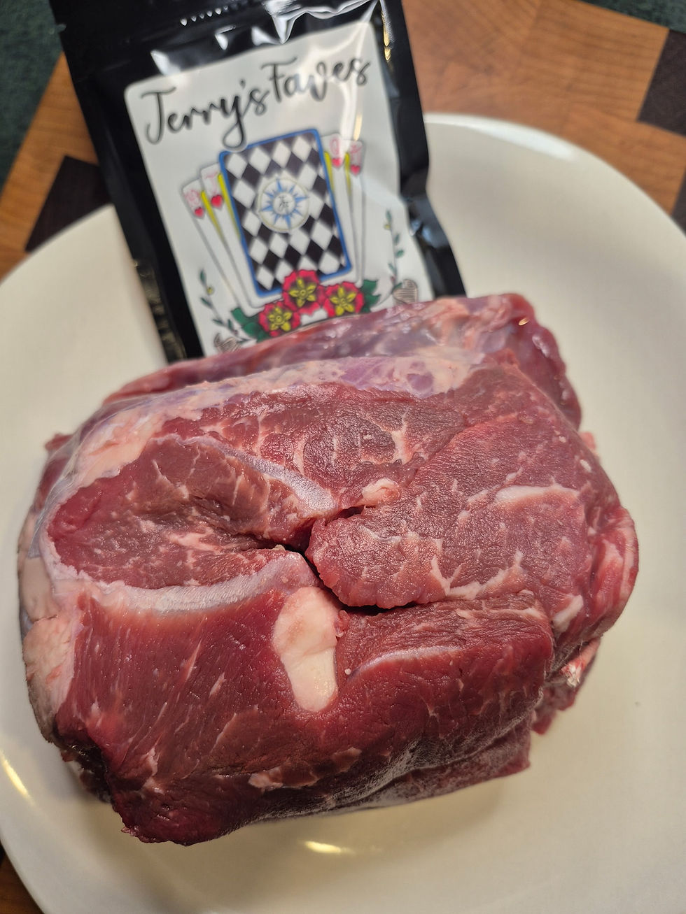 Raw beef roast on a prep surface beside a package of No Bull dry rub, ready for seasoning before cooking.