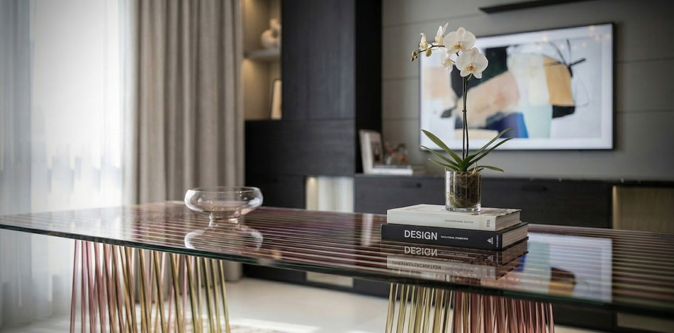 Contemporary glass desk with sculptural base styled with books and decorative objects.