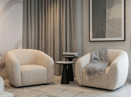 Curved accent chairs and side table seating vignette in a neutral guest bedroom design.