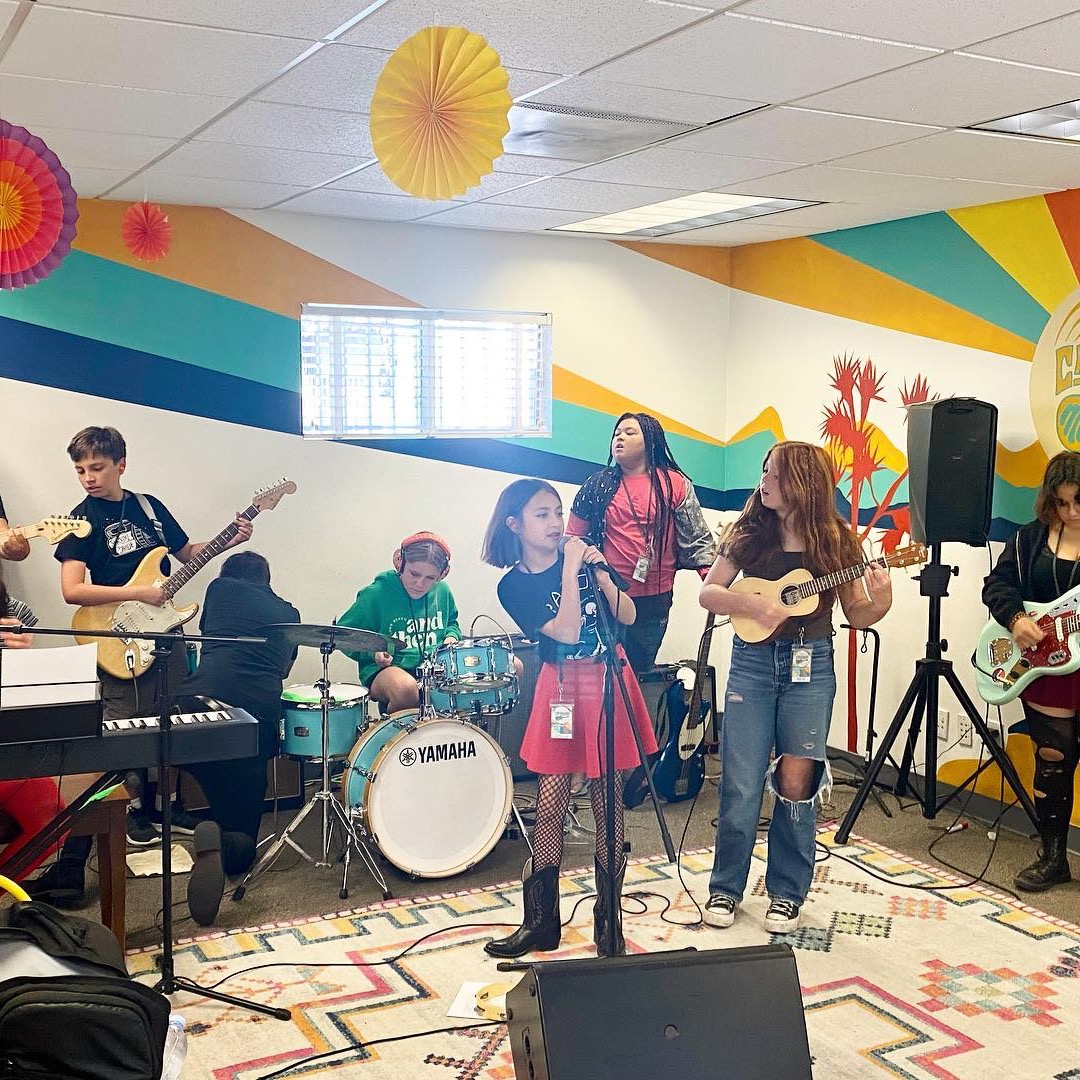 Teen band performing together — guitar, drums, bass, keys and vocals in the studio