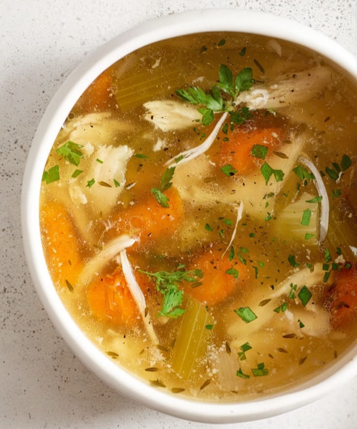 High angle view of a steaming bowl of Csirkeleves with fresh vegetables and chicken pieces