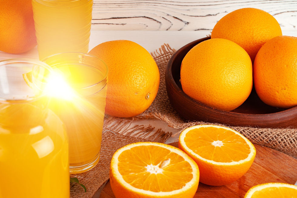 mesa com cesto de laranjas ao lado de um copo de suco de laranja