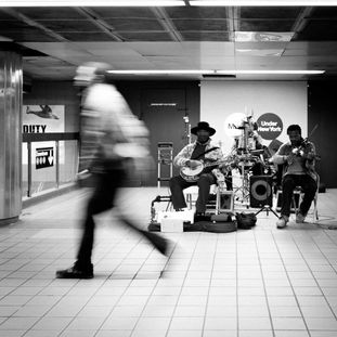 homme passant devant un groupe de musique dans le métro de new york