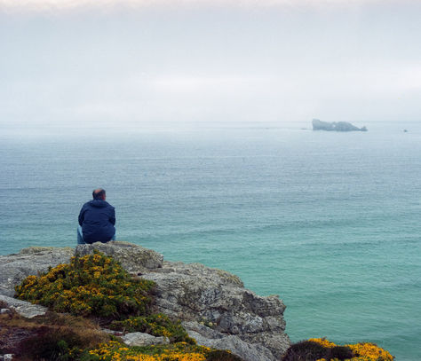 bretagne homme de dos regardant l'océan assis sur rocher