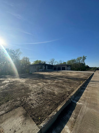 Construction site, clear skies and bright sun over a large empty lot.