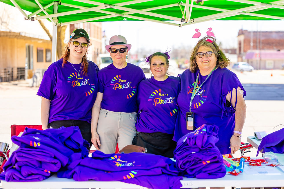 Four people in purple shirts at an outdoor event booth.