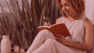 A woman journalling in a calm and natural setting.