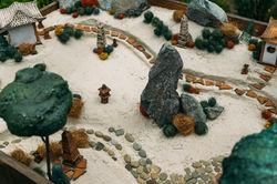 Miniature houses, toy landscape objects on the sand. Sand therapy