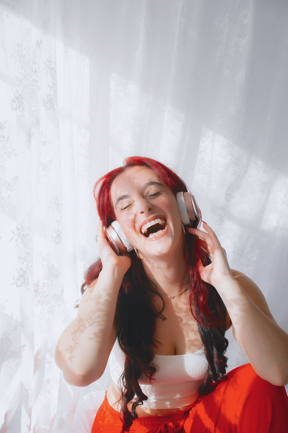 headphones on woman listening to creativity podcast with a large smile