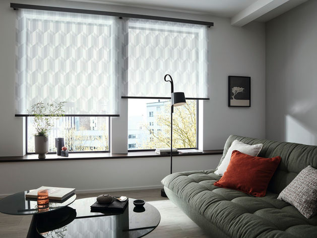 Modernes Wohnzimmer mit grauem Sofa, Kaffeetisch, Fenstern mit weißen Jalousien.