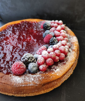 Deliziosa cheesecake con frutti di bosco freschi, glassa rossa e spolverata di zucchero