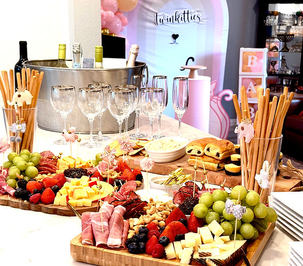 “Event charcuterie display with assorted cheeses, fruits, cured meats, nuts, breadsticks, and themed baby shower decorations.”