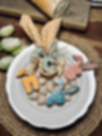 Segnaposto pasquale in legno a forma di coniglietto con iniziali personalizzate in colori pastello su piatto decorativo.