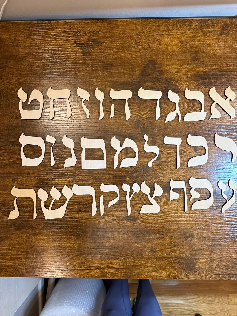 Custom wooden Hebrew alphabet letter cutouts on a table.
